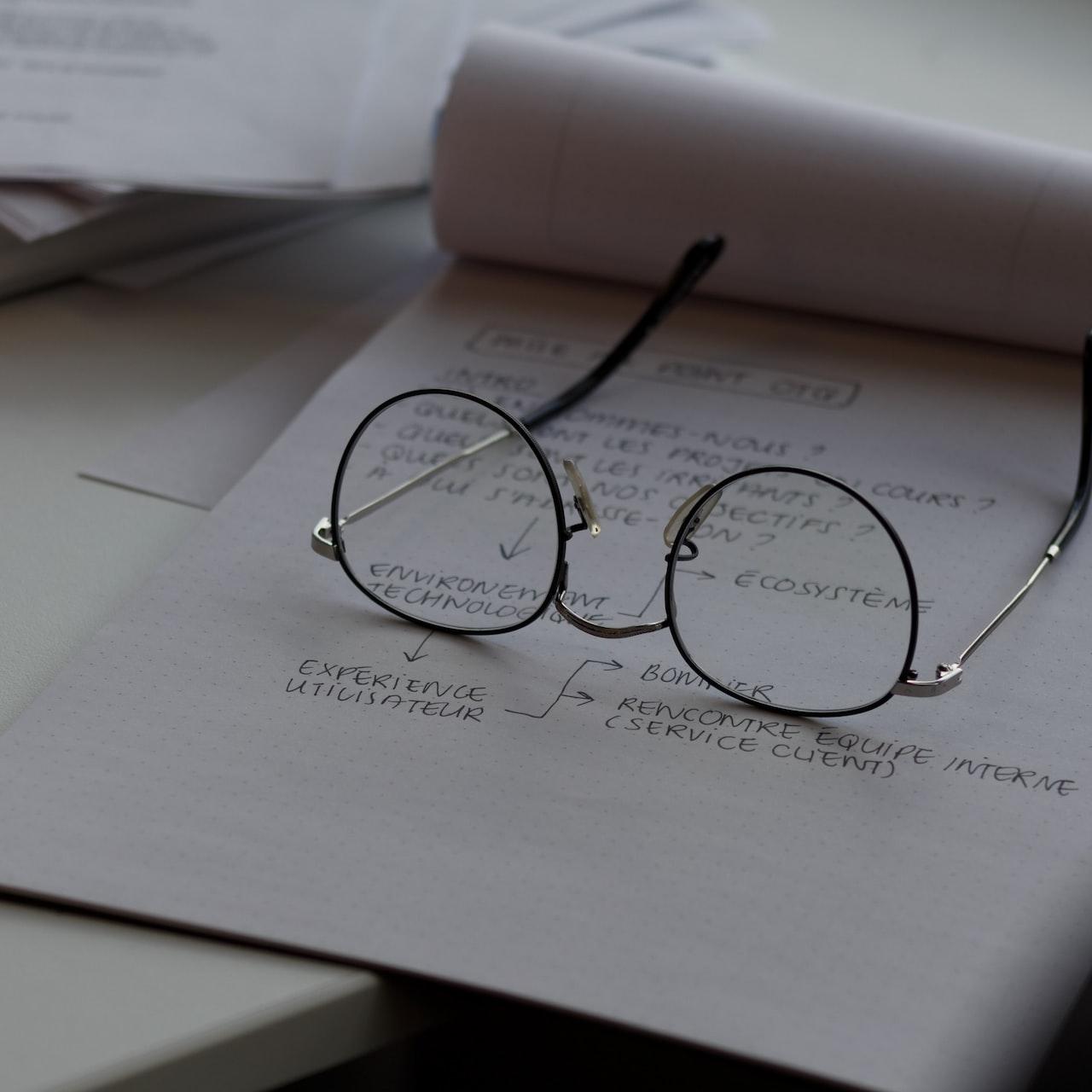 black framed eyeglasses on top of white printing paper